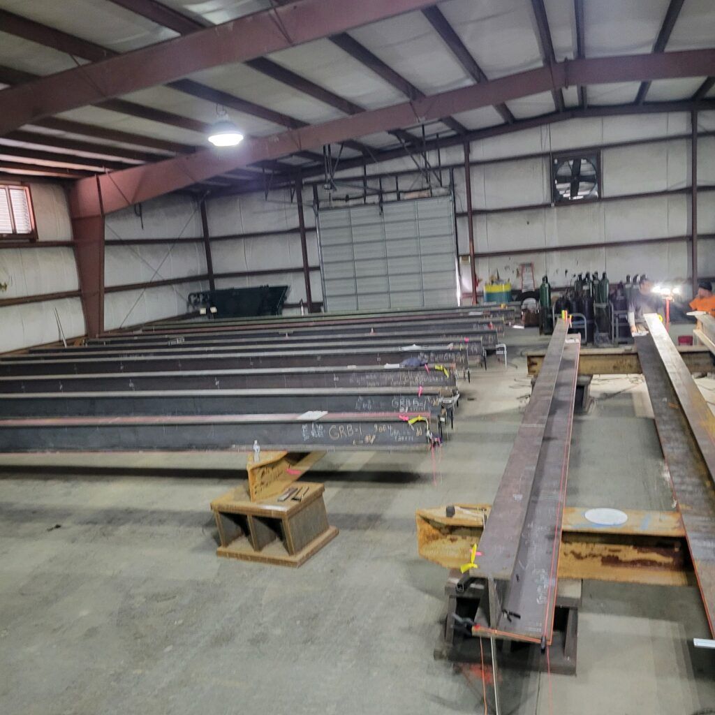 Interior of an industrial workshop with steel beams and construction materials, reflecting positive customer feedback on the wall.