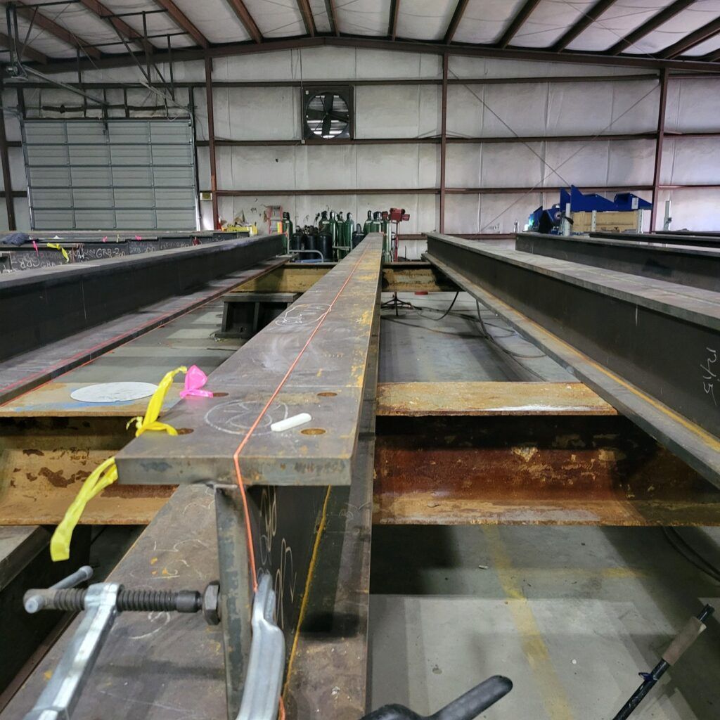 An industrial workshop with steel beams in preparation for fabrication, enhanced by positive customer testimonials regarding the quality of work.