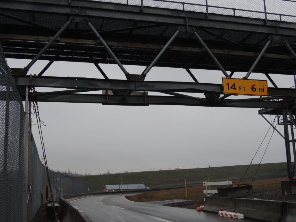 Overcast weather conditions with a steel overpass displaying a height clearance sign of 14 feet 6 inches above a wet roadway, garnering positive feedback.