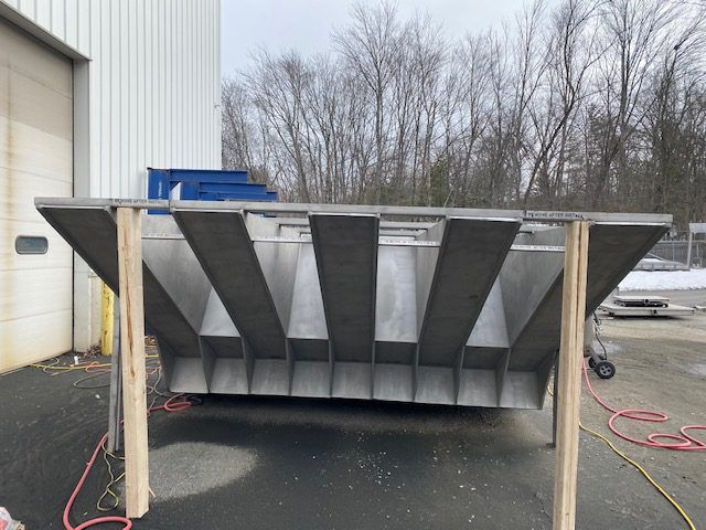 Industrial metal hopper supported by wooden stands outside a building, highly praised in customer feedback.