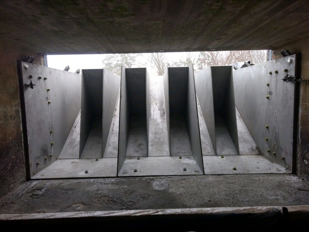 A view from inside a concrete structure with symmetrical openings allowing light to enter, adorned with testimonials.